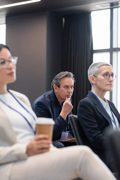 Businessman with paper folder sitting near colleagues in conference room — Stock Photo