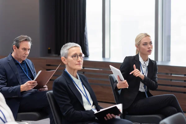 Geschäftsfrau zeigt im Konferenzraum auf digitales Tablet neben Kollegen — Stockfoto