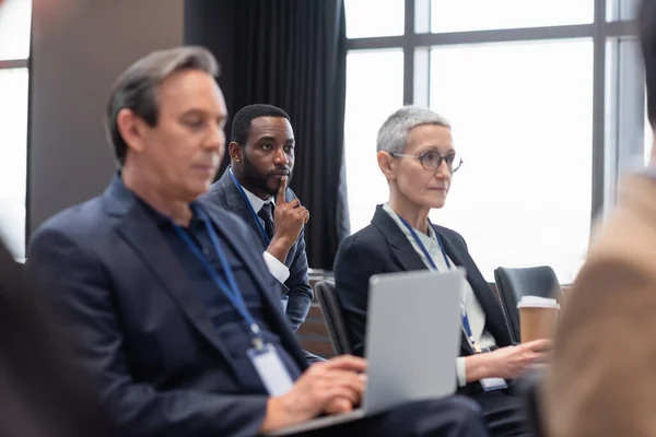African american businessman looking away during seminar near colleagues — Stock Photo