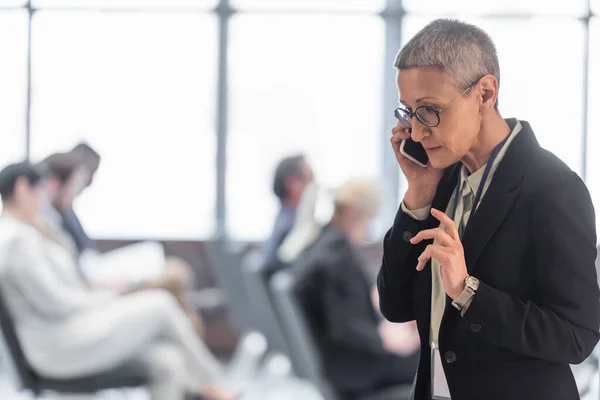 Middle aged businesswoman talking on mobile phone during conference — Stock Photo