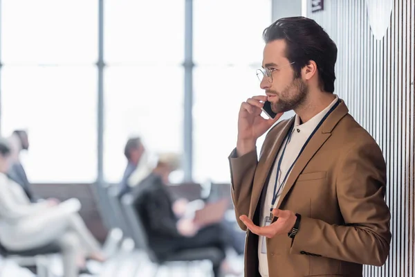 Вид збоку молодого бізнесмена, що розмовляє по мобільному телефону біля конференц-залу — стокове фото