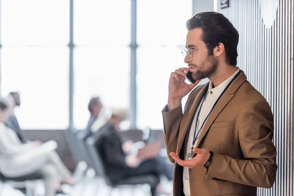 Side view of young businessman talking on mobile phone near conference room — Stock Photo