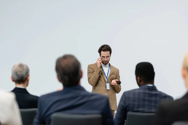 Haut-parleur avec microphone debout près des gens d'affaires multiethniques — Photo de stock