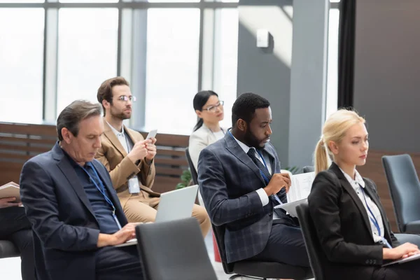 Afrikanischer Geschäftsmann schaut sich während eines Seminars im Konferenzraum Dokumente an — Stockfoto