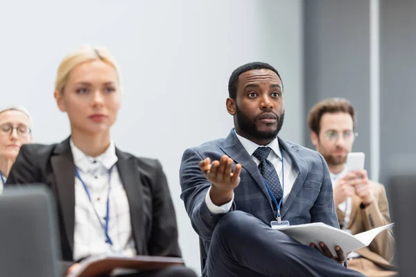 Empresário afro-americano com papéis apontando com a mão durante reunião na sala de conferências — Fotografia de Stock