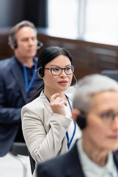 Asian businesswoman in headset sitting in conference room during training — Stock Photo