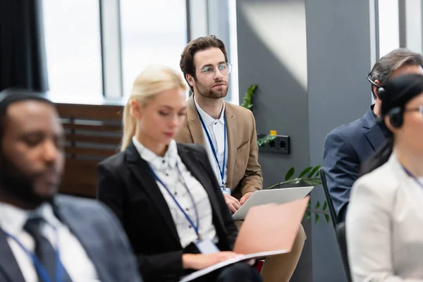 Empresario usando laptop cerca de colegas interracial en sala de conferencias - foto de stock