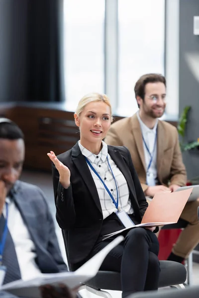 Smiling businesswoman with paper folder talking in conference room — Stock Photo