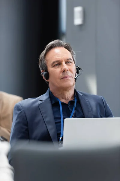 Homme d'affaires d'âge moyen dans casque assis avec ordinateur portable dans la salle de conférence — Photo de stock