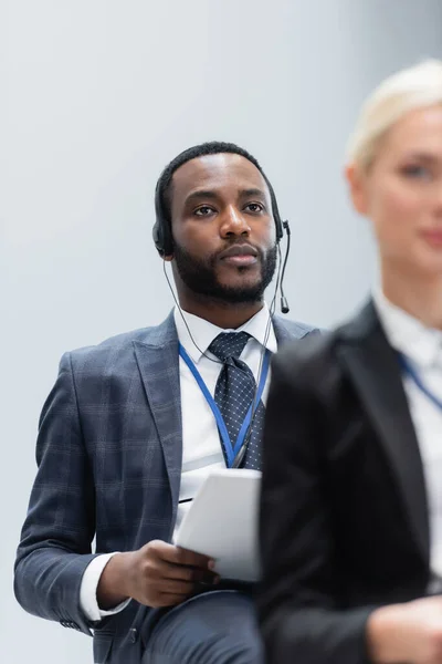 Foco seletivo do empresário afro-americano em headset perto de empresária em primeiro plano turvo — Fotografia de Stock