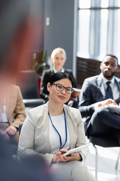 Interracial business people listening to lecturer on blurred foreground — Stock Photo