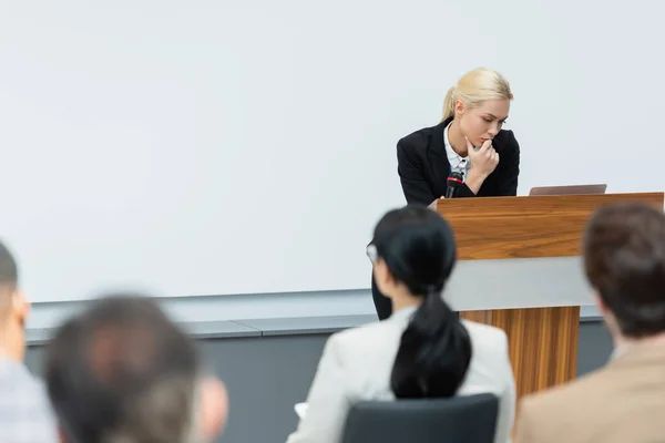 Vista posterior de la gente de negocios cerca de profesor reflexivo mirando el ordenador portátil durante el seminario - foto de stock