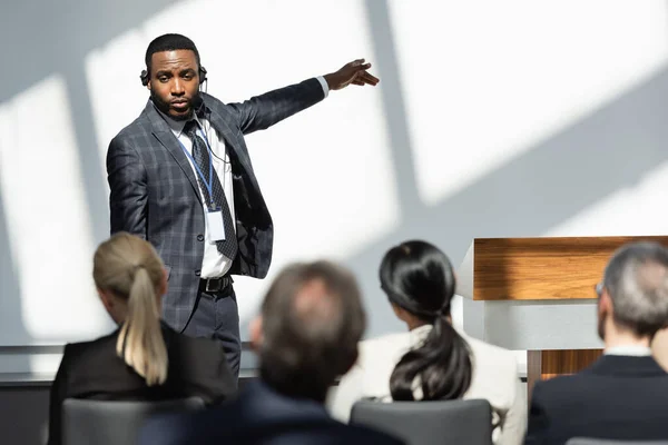 Rückansicht von Geschäftsleuten in der Nähe eines afrikanisch-amerikanischen Vortragenden, der während der Konferenz mit dem Finger zeigt — Stockfoto