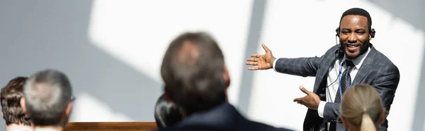 Vista posteriore di uomini d'affari vicino afro-americano docente che punta con le mani durante il seminario, banner — Foto stock