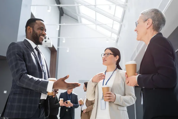 Happy african american businessman pointing with hand near interracial businesswomen — Stock Photo