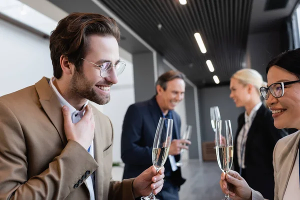 Joven empresario celebración champán durante conversación con asiático colega - foto de stock