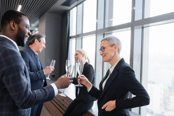 Interrazziale uomini d'affari clinking champagne bicchieri durante la pausa in conferenza — Foto stock