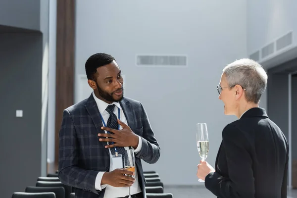 Afrikanisch-amerikanischer Geschäftsmann hält Hand auf Brust während eines Gesprächs mit einem Kollegen mittleren Alters — Stockfoto