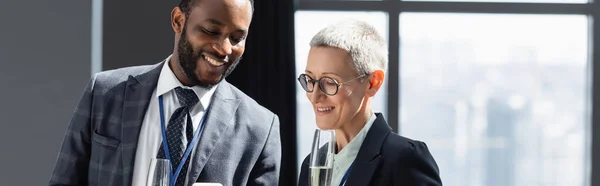 Sonriente gente de negocios multiétnicos sonriendo mientras habla en la oficina, pancarta - foto de stock