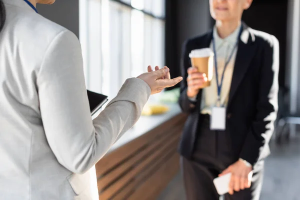 Cropped view of businesswoman gesturing near middle aged colleague on blurred background — Stock Photo