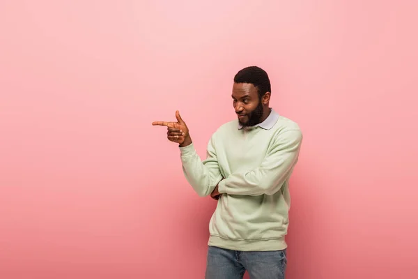 Усміхнений афроамериканець вказує на рожевий фон. — стокове фото