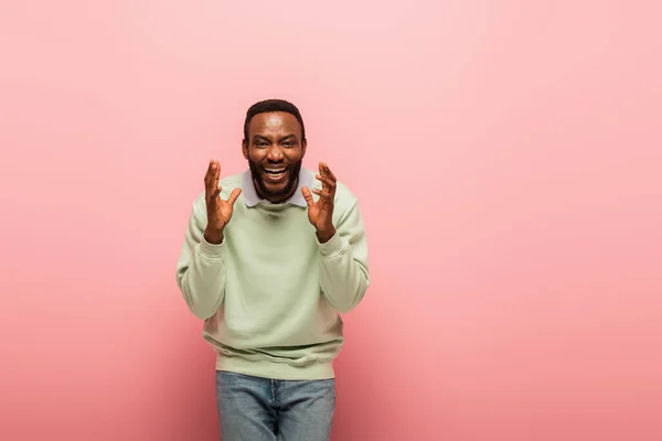 Positive african american man laughing and looking at camera on pink background — Stock Photo