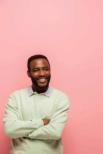 Sorrindo afro-americano com braços cruzados olhando para câmera isolada em rosa — Fotografia de Stock