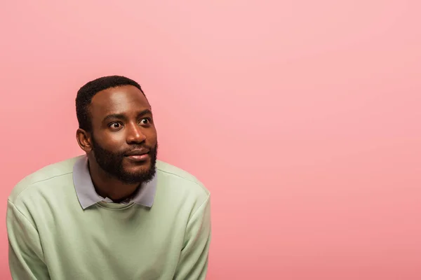 Afroamericano uomo in maglione verde guardando lontano isolato su rosa — Foto stock