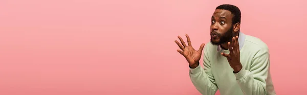 Scioccato uomo afroamericano guardando altrove isolato sul rosa, striscione — Foto stock
