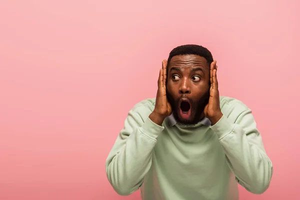 Приголомшений афроамериканець, що дивиться геть, ізольований на рожевому — стокове фото
