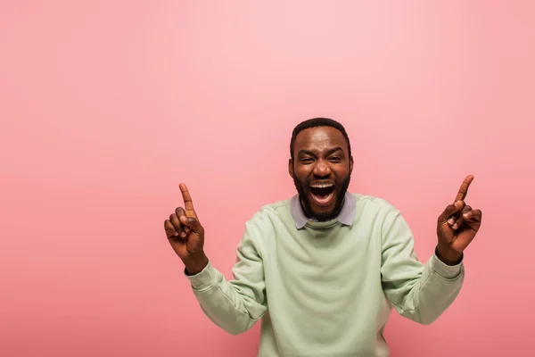 Aufgeregter afrikanisch-amerikanischer Mann zeigt mit Fingern auf rosa — Stockfoto