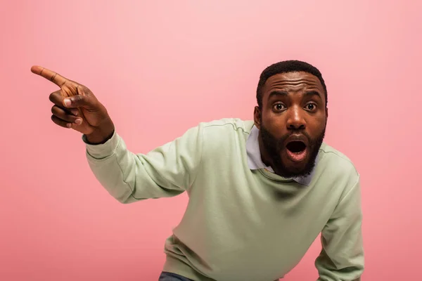 Hombre afroamericano asombrado señalando aislado en rosa - foto de stock