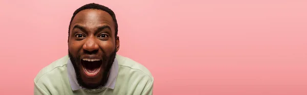 Astonished african american man looking at camera isolated on pink, banner — Stock Photo