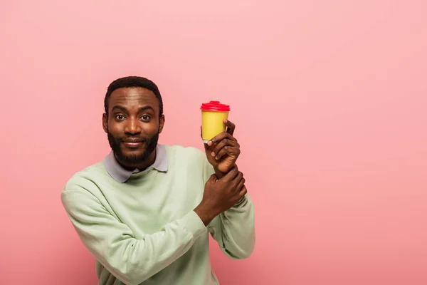 Afrikanisch-amerikanischer Mann mit Kaffee zu gehen Blick auf Kamera isoliert auf rosa — Stockfoto