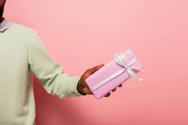Vista cortada do homem americano africano com caixa de presente sobre fundo rosa — Fotografia de Stock