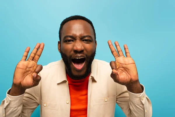 Amazed african american man showing okay signs while looking at camera isolated on blue — Stock Photo
