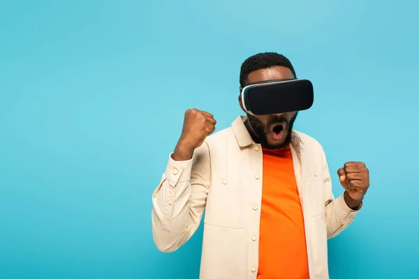 Excité homme afro-américain dans vr casque montrant geste gagnant isolé sur bleu — Photo de stock