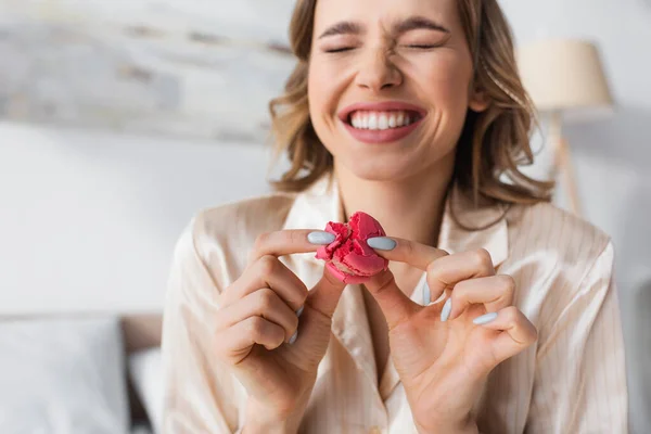 Macaroon in mani di donna allegra su sfondo sfocato — Foto stock