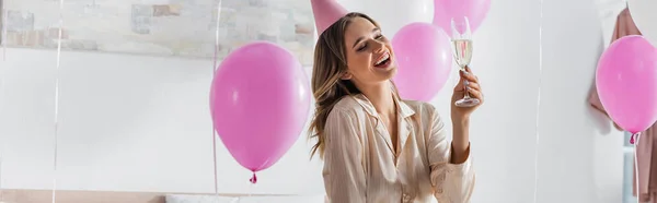 Donna felice con champagne che festeggia il compleanno vicino ai palloncini a casa, banner — Foto stock