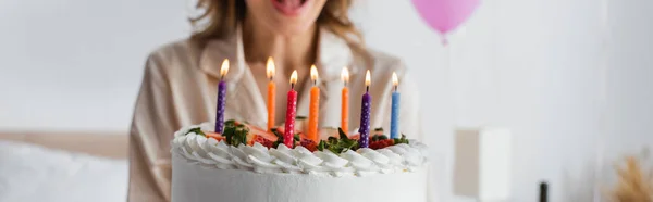 Cropped view of birthday cake with candles near blurred woman, banner — Stock Photo