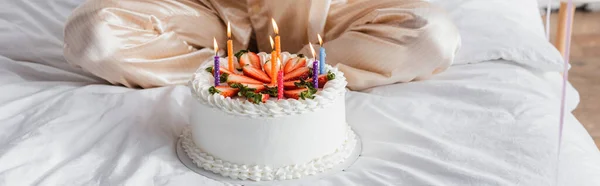 Ausgeschnittene Ansicht der Geburtstagstorte mit Kerzen in der Nähe der Frau auf dem Bett, Banner — Stockfoto