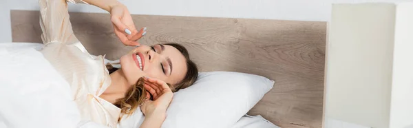 Positive Frau mit geschlossenen Augen auf dem Bett liegend, Banner — Stockfoto