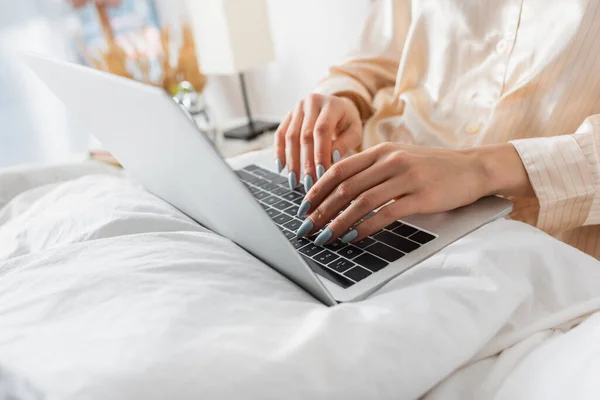 Cropped view of woman in pajama using laptop on blanket — Stock Photo