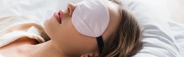 Mujer joven con máscara de dormir en la cama, pancarta - foto de stock