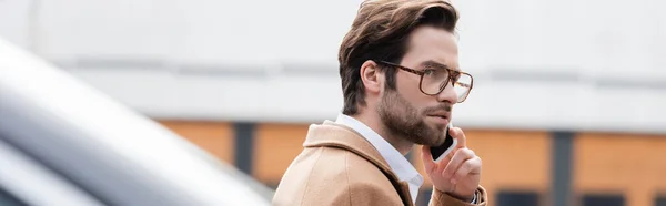 Homme d'affaires confiant dans des lunettes parler sur téléphone portable à l'extérieur, bannière — Photo de stock