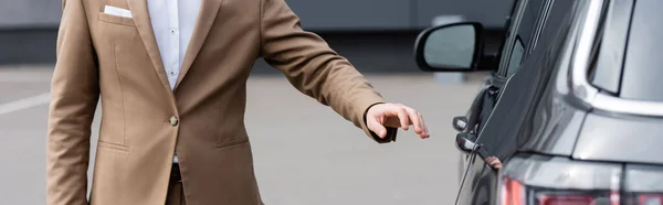 Abgeschnittene Ansicht eines Mannes in beiger Jacke, der die Autotür erreicht, Banner — Stockfoto