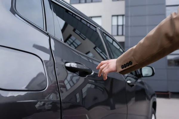 Vista parcial del hombre de negocios en traje beige que llega a la puerta del coche - foto de stock