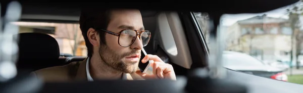 Man in glasses talking on smartphone in car, banner — Stock Photo