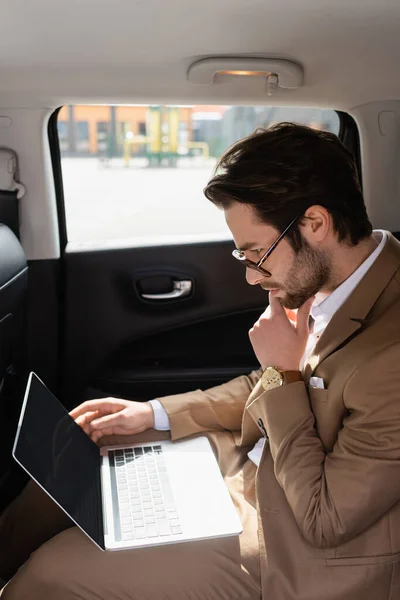 Hombre de negocios pensativo en gafas trabajando a distancia en el coche - foto de stock