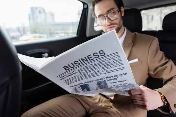 Mann mit Brille liest Wirtschaftszeitung im Auto — Stockfoto